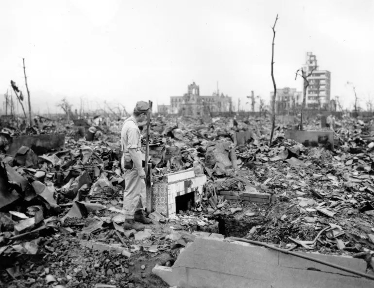 a man stands next to a tiled fireplace where a house once stood in hiroshima, japan, on september 7, 1945. the vast ruin was caused by the uranium atomic bomb detonated on august 6 by the us, leading to the end of world war ii [stanley troutman/ap]