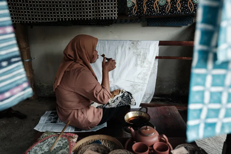 a craftswoman makes traditional batik using a tool with melted wax to draw patterns on fabric at a local batik shop in surakarta, central java, on july 30, 2024 [yasuuoshi chiba/afp]