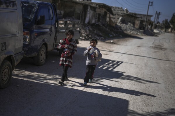 two girls walk past destroyed homes in the town of tel rifaat in the aleppo region of northern syria, tuesday, jan. 28, 2025. (ap photo/khalil hamra)