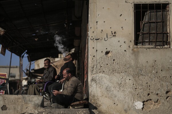 men, one smoking a hookah, sit outside a shop in the town of tel rifaat in the aleppo region of northern syria, tuesday, jan. 28, 2025. (ap photo/khalil hamra)